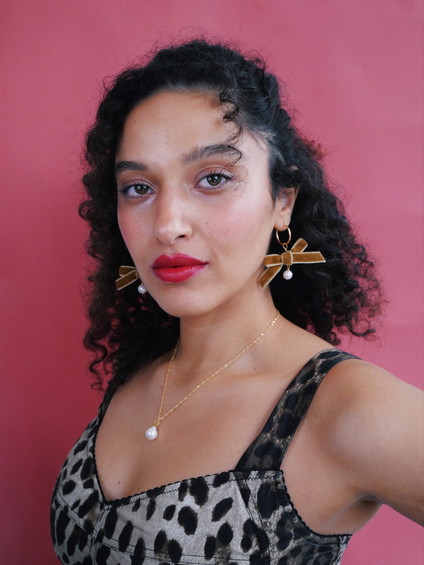 Curled hair model  leopard shirt white pear and bow earrings 14K gold necklace