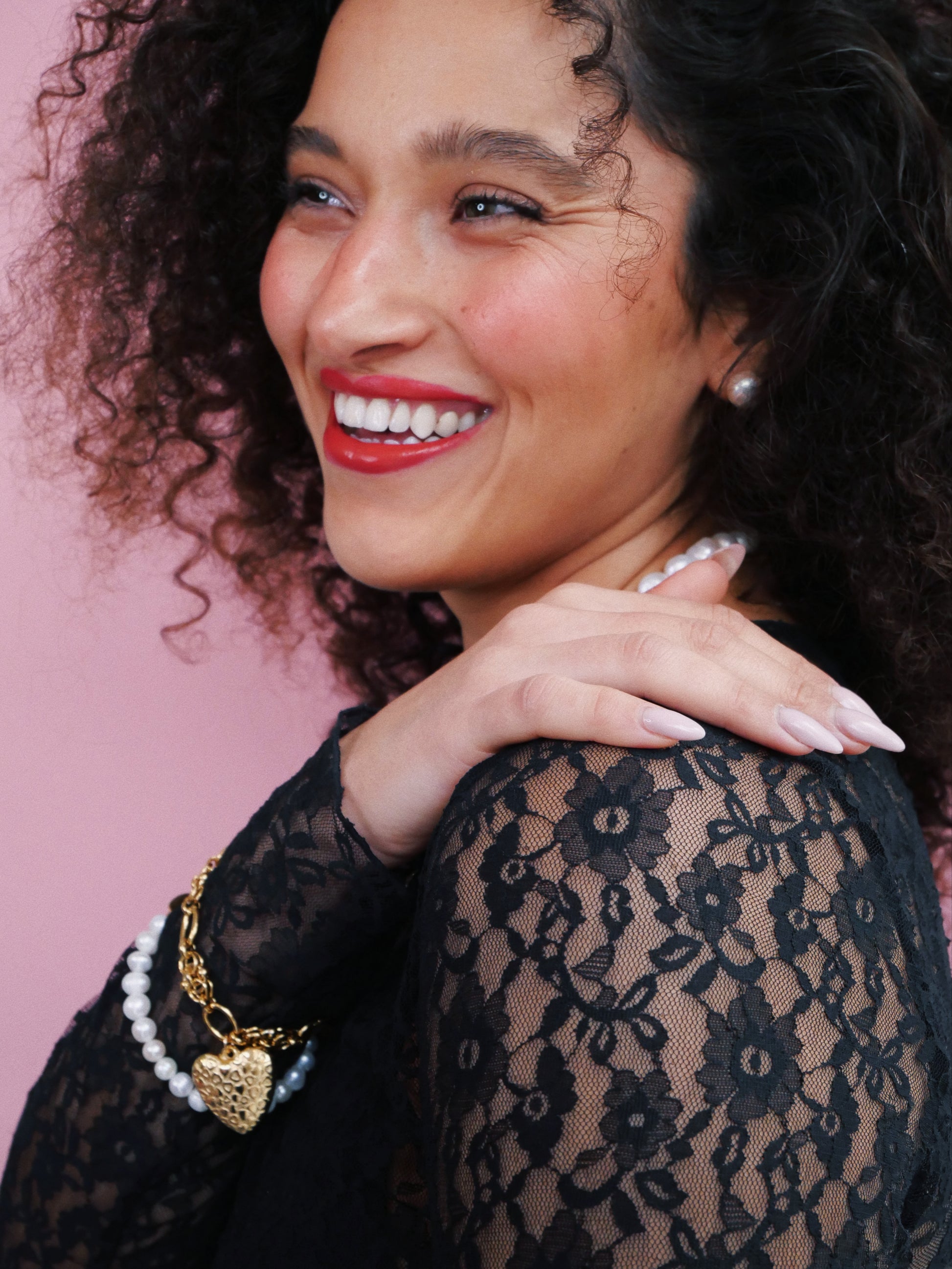 Curled hair model  lace shirt white pearl and 14K gold heart bracelets and white pearl earrings white pearl necklace